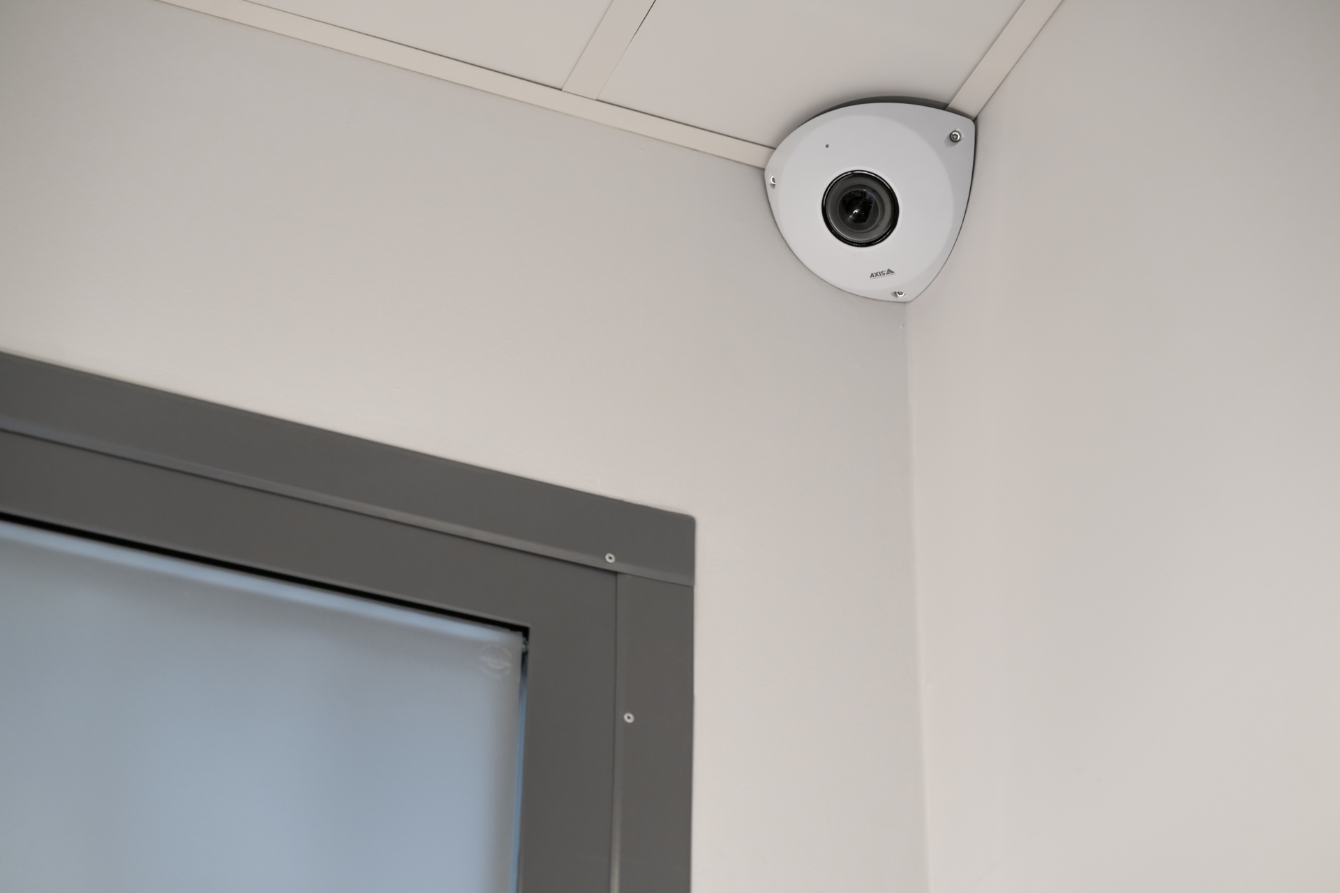 AXIS P9117-PV Corner Camera in white polycarbonate finish, shown from two angles - front three-quarter view and side profile - with a stereographic dome lens for 360° panoramic coverage.