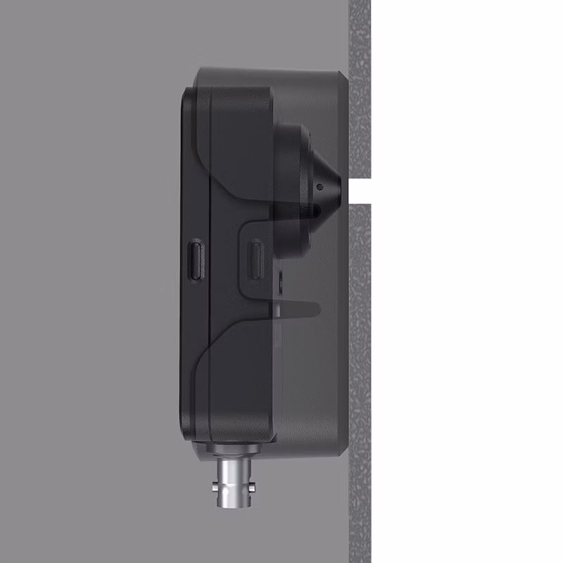A side-view technical rendering of an Avigilon H5A Modular Camera pinhole sensor mounted behind a wall, showing the lens aligned with a small aperture for covert surveillance.