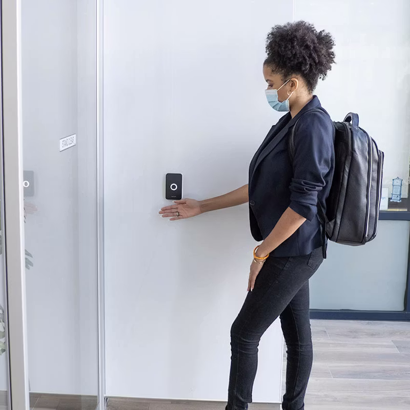 Woman utilizing the wave-to-unlock feature on an Avigilon Alta access control reader for secure, touchless entry.