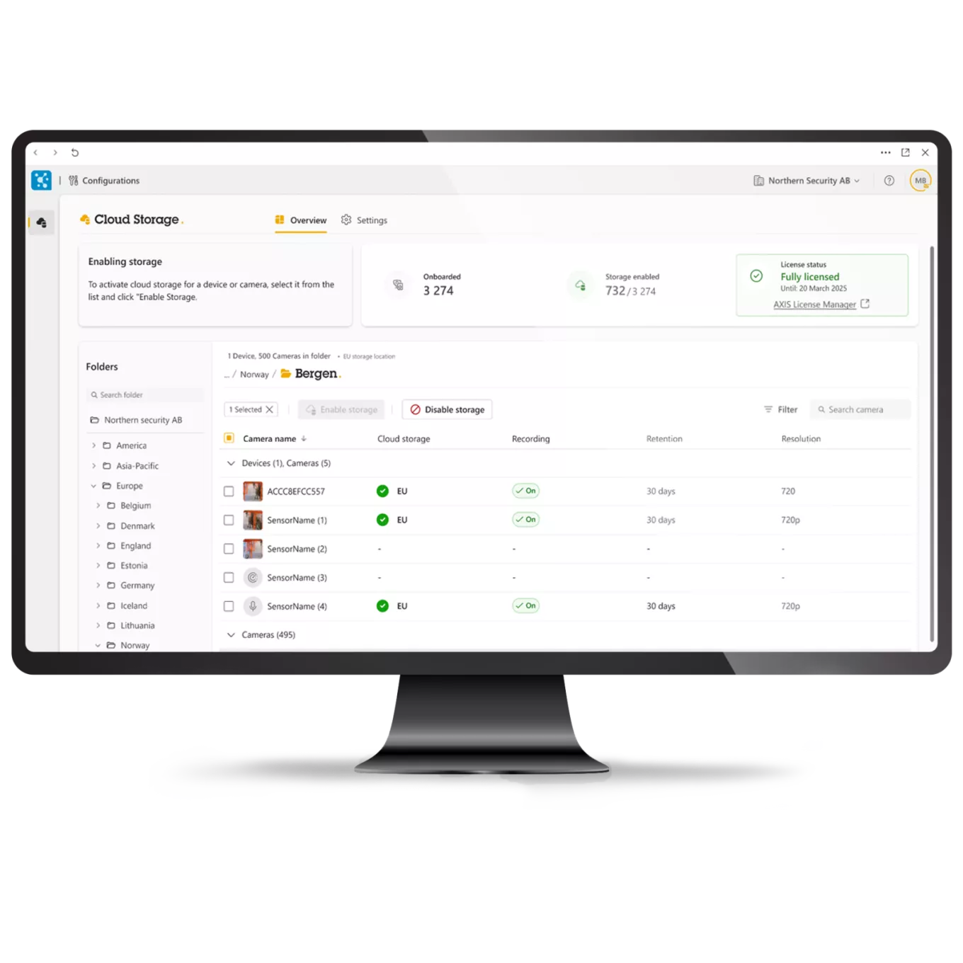 A computer monitor displaying the AXIS Camera Station Cloud Storage dashboard, showing camera deployment folders, recording status, 30-day retention policies, and active license information.