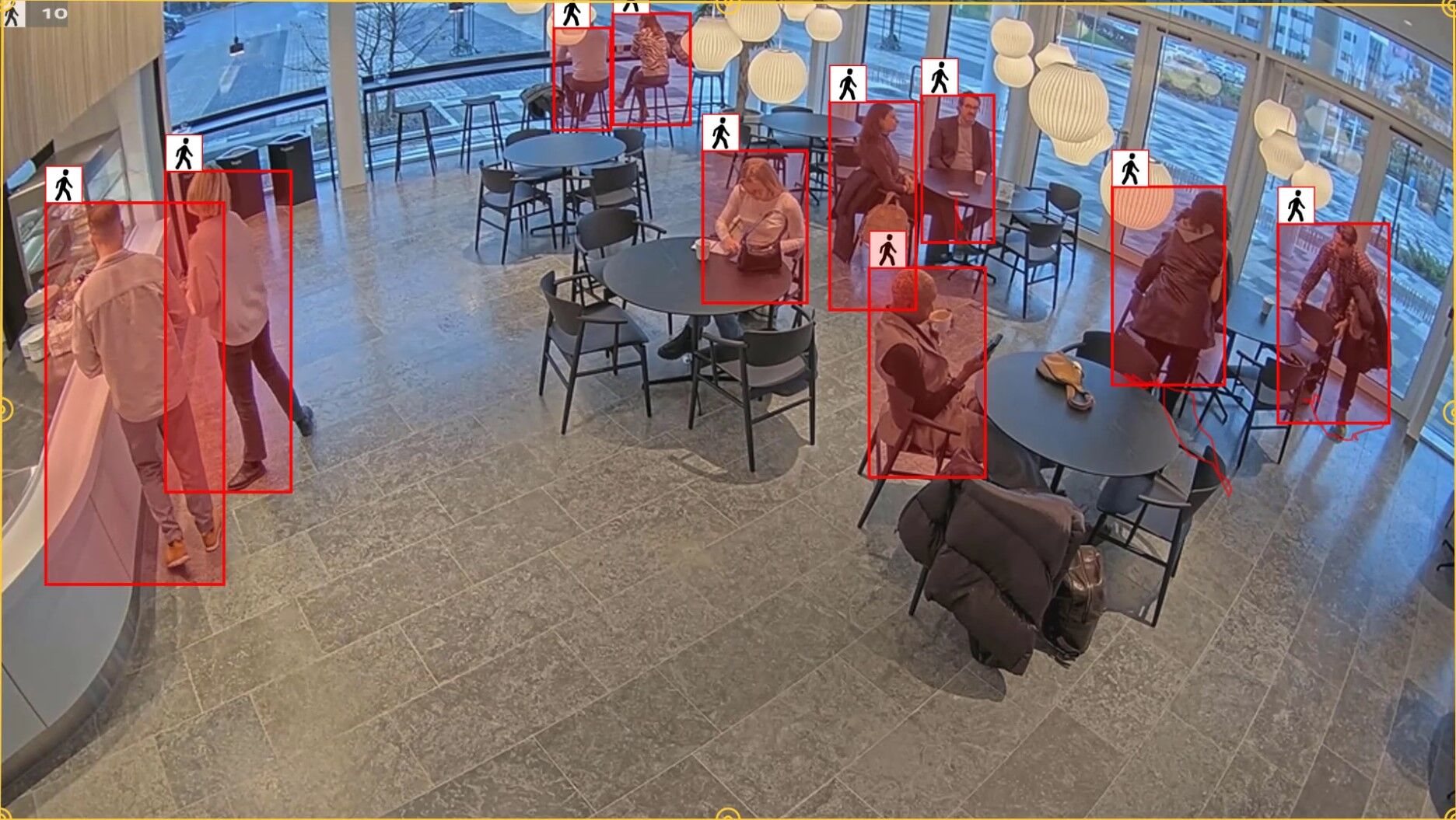 Security camera view demonstrating AXIS Object Analytics detecting and tracking individuals within a defined retail area using active bounding boxes.