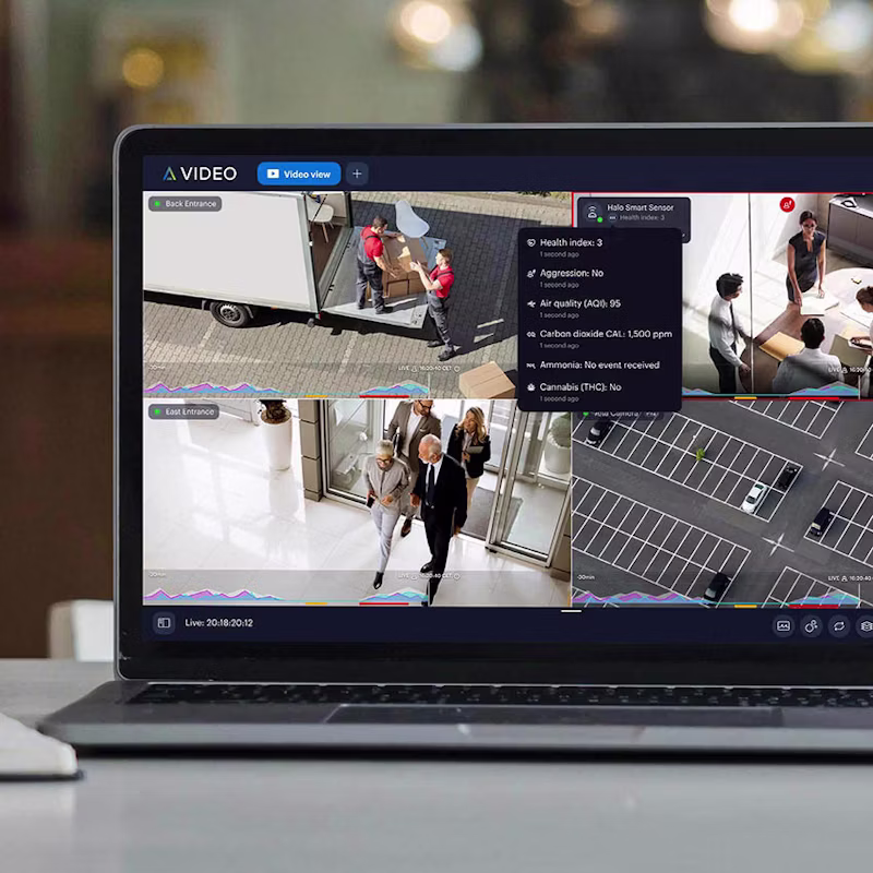 A laptop screen displaying a multi-view video surveillance dashboard with live feeds and a smart sensor data overlay.