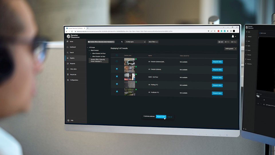 A person looking at a desktop monitor displaying the Genetec Clearance software interface, showing a registry of security cameras with multiple camera feeds selected for a video request.