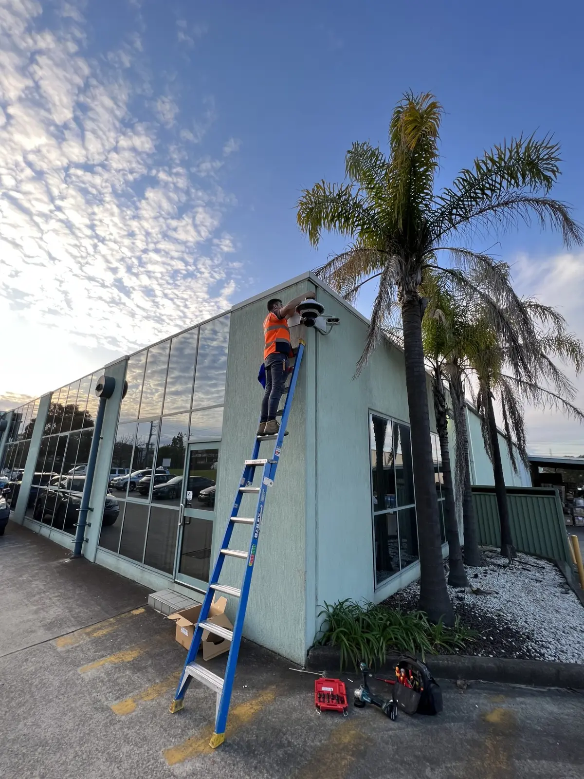 JD Security technician performing security system maintenance on a dome CCTV camera at a commercial building